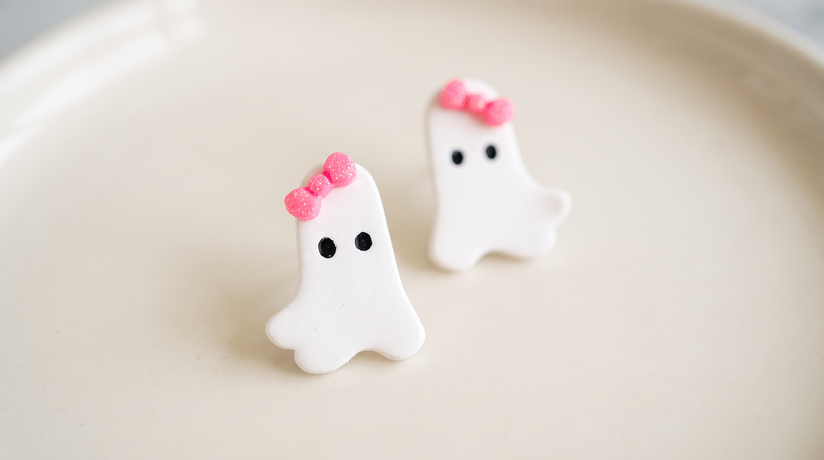 Two matching white ghost-shaped stud earrings, flat lay